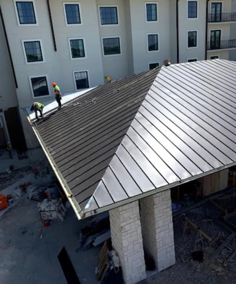 Crew installing standing seam metal roof panels on a commercial project in Fort Irwin